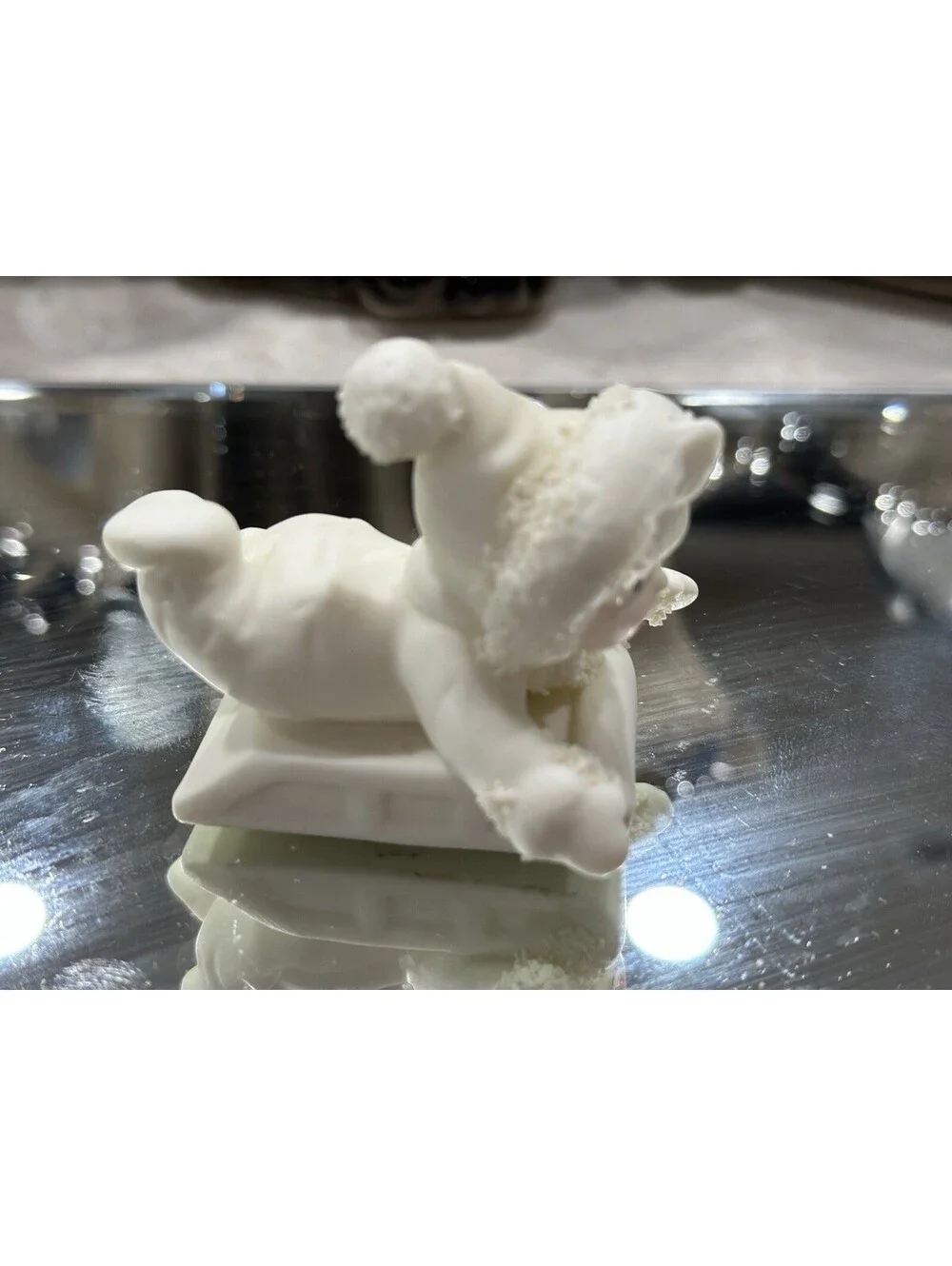 Department 56 Snowbabies figurine shows a baby dressed in a snowsuit playing